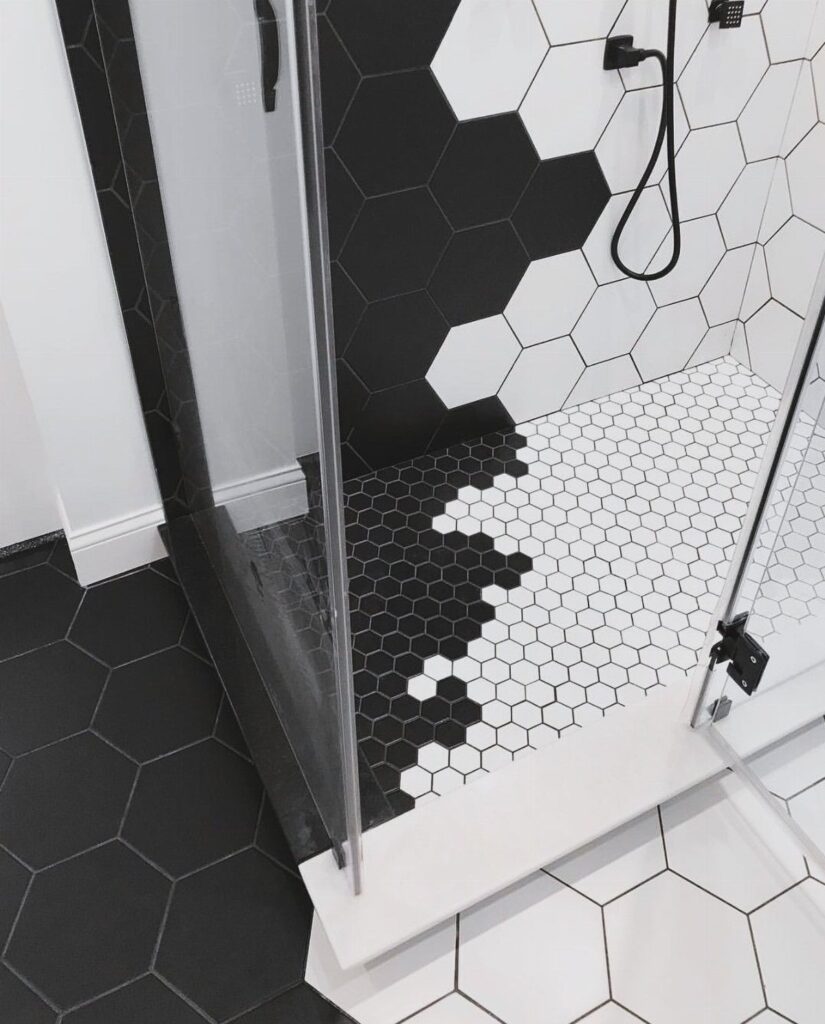Black and white hexagon tiles on a shower wall and floor.