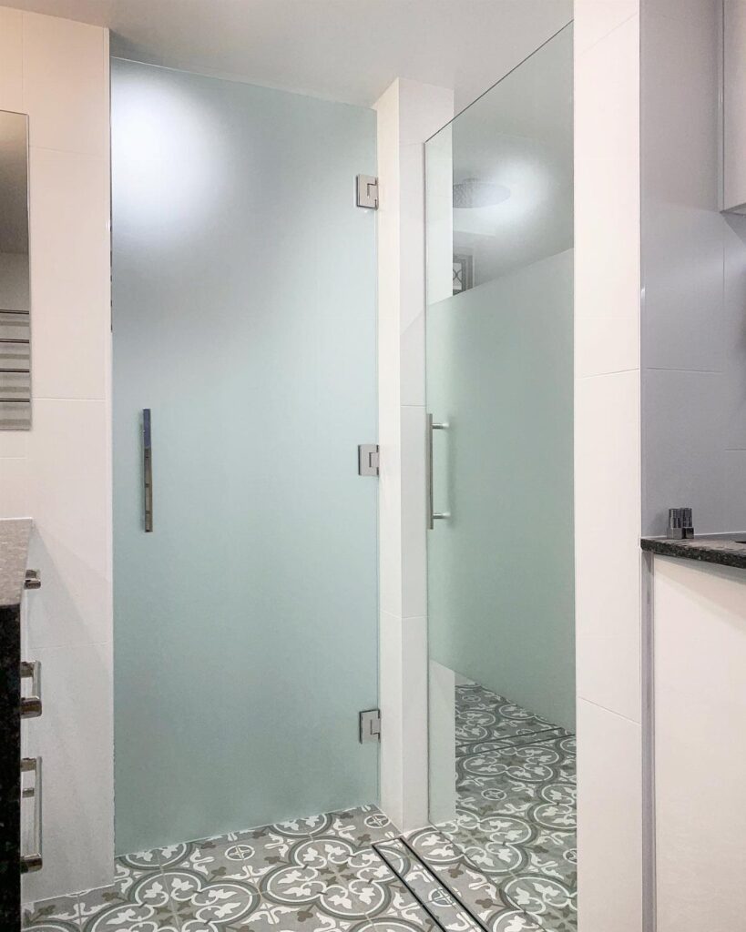 Frosted glass shower door in a bathroom with patterned grey and white floor tiles.