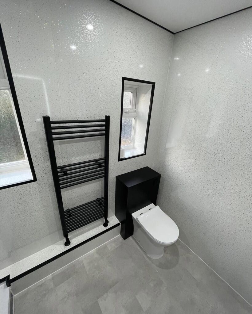 Modern bathroom with white shimmering walls, black towel rail, and white toilet.
