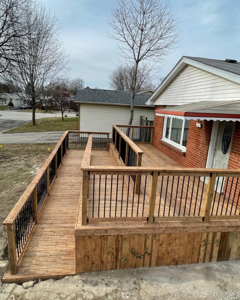 Wooden accessibility ramp with black railings leading to a house entrance deck.