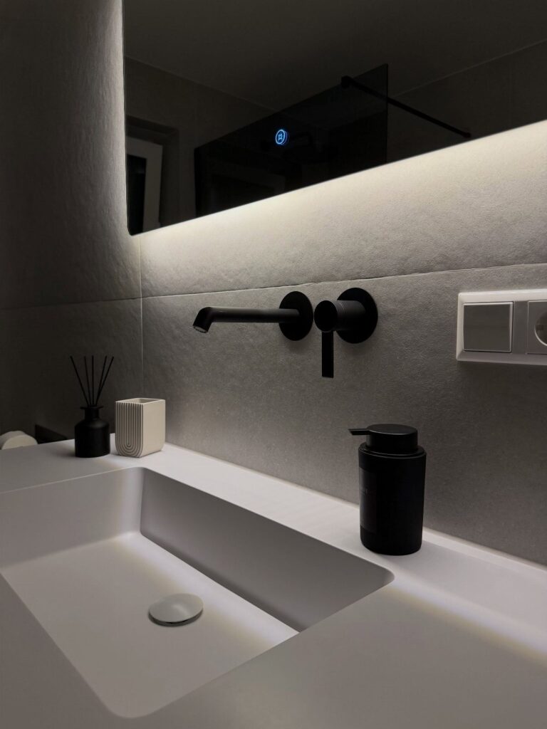 White rectangular sink with a matte black wall-mounted faucet and black accessories.