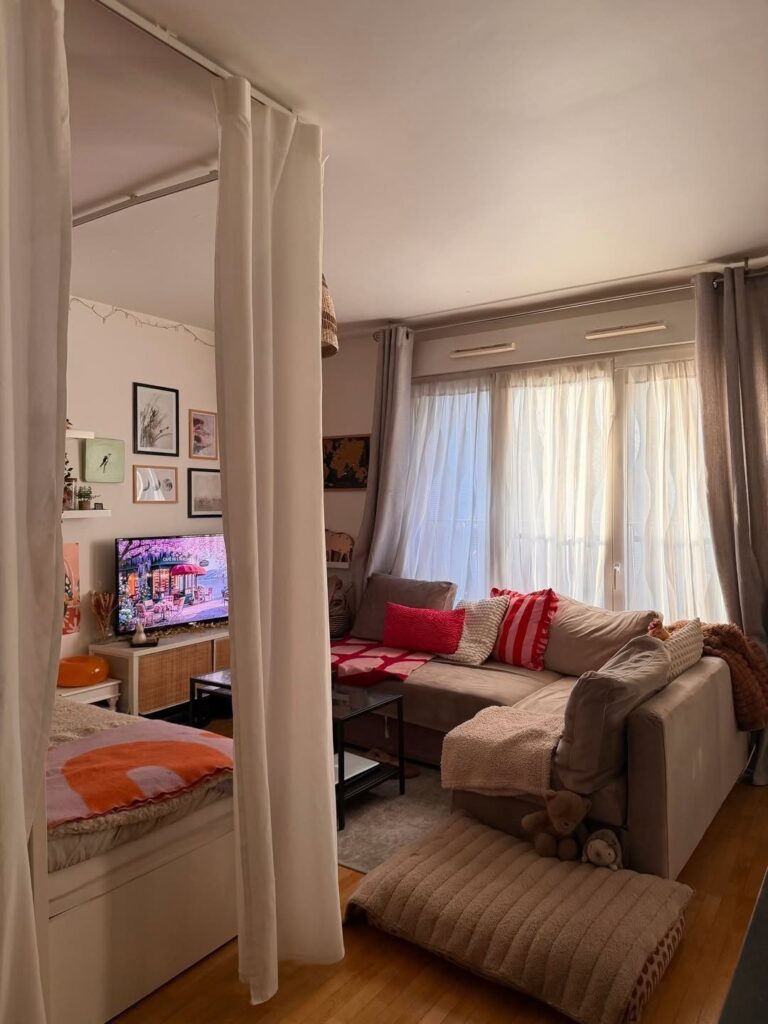 Small studio apartment with a white curtain divider separating the bed and living area.