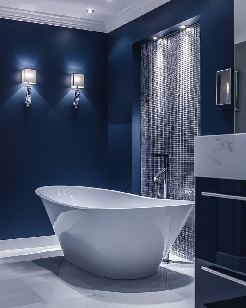 White freestanding bathtub in a modern bathroom with deep blue walls and mosaic tiles.