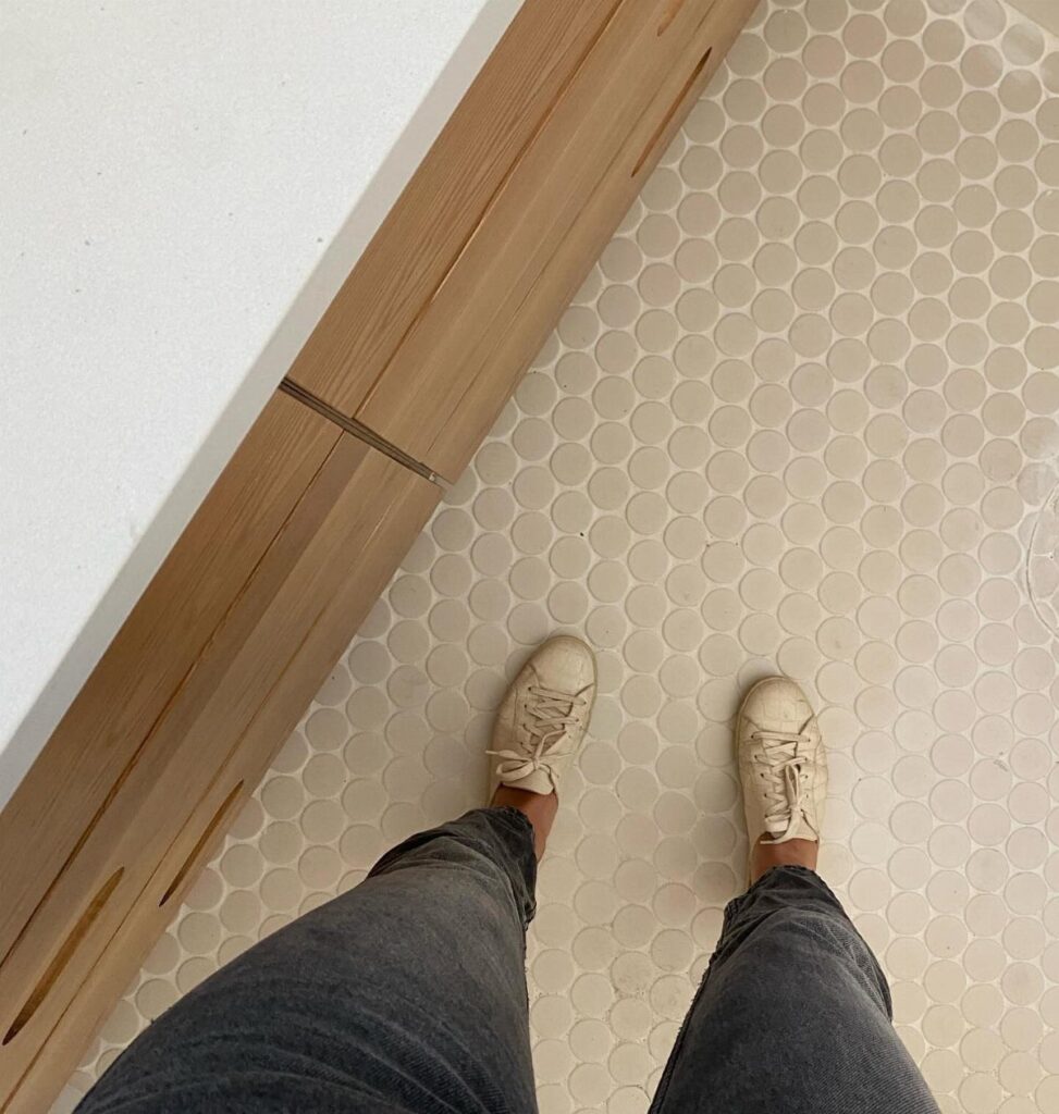 Small off-white penny round floor tiles next to a light wood baseboard.