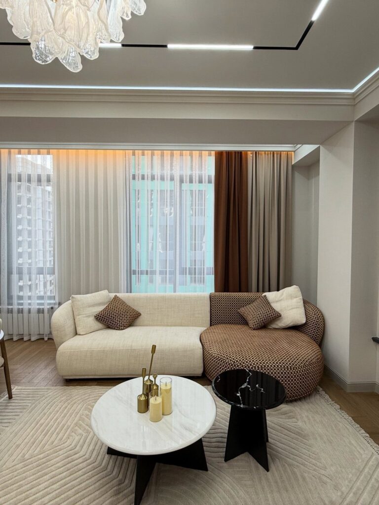 Modern living room with a textured sectional sofa, marble table, and crystal chandelier.