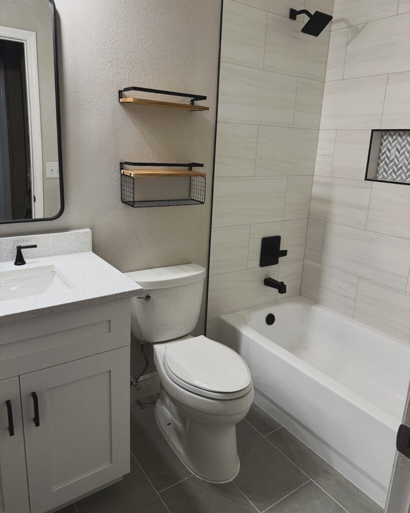 Small bathroom with white vanity, toilet, and bathtub with white tiled walls.