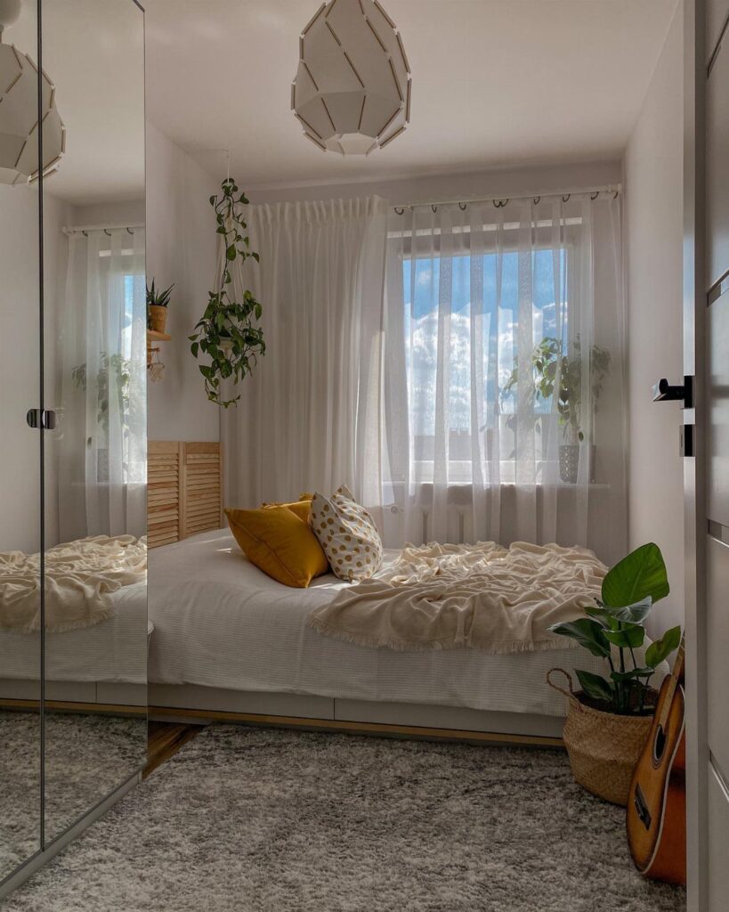 Bright small bedroom with sheer white curtains allowing natural light to fill the space.