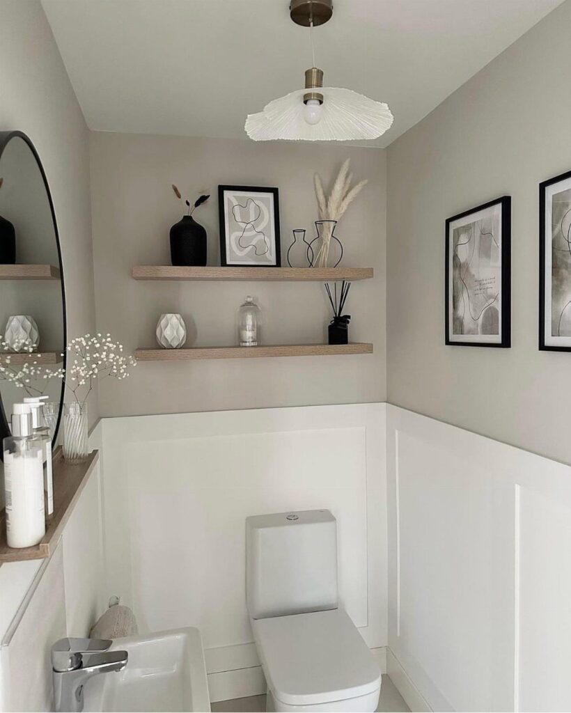 Small powder room with grey walls, white wainscoting, and wooden floating shelves.