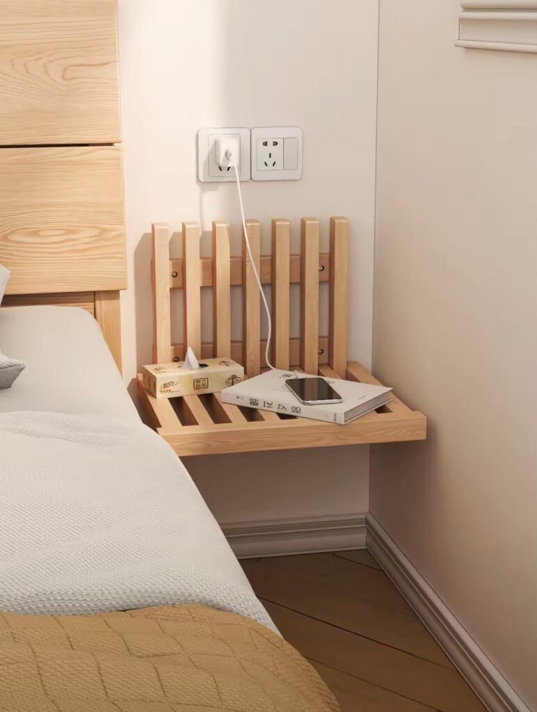 Wooden floating bedside shelf with a book and phone next to a bed