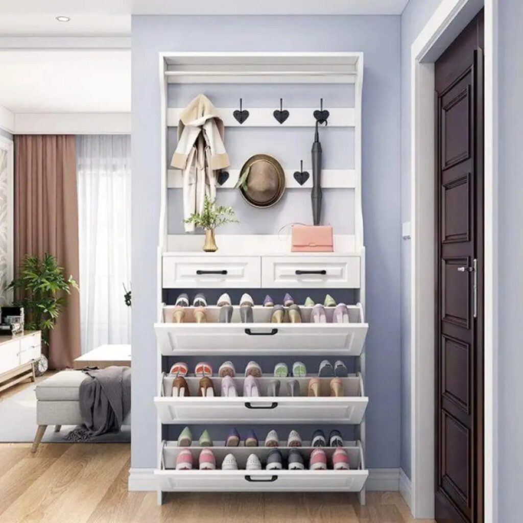 White entryway storage unit with shoe racks and coat hooks against blue wall
