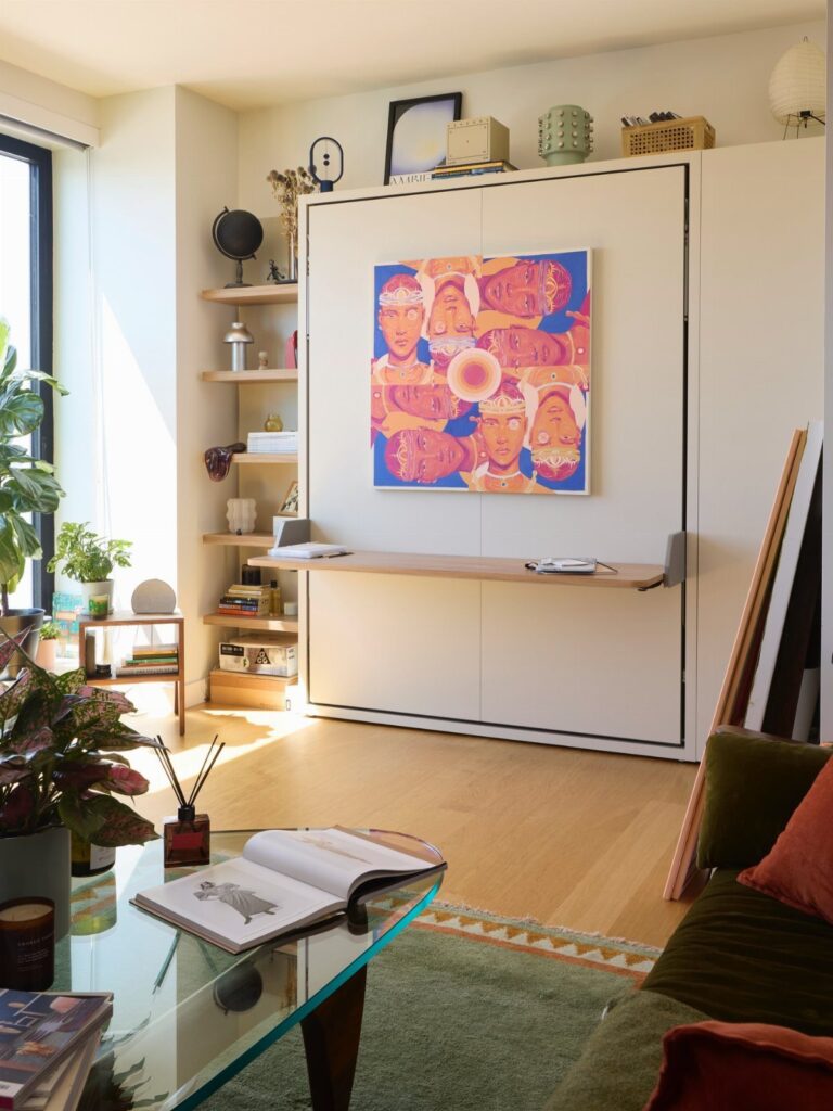White Murphy bed folded up with a built-in desk in a bright studio.