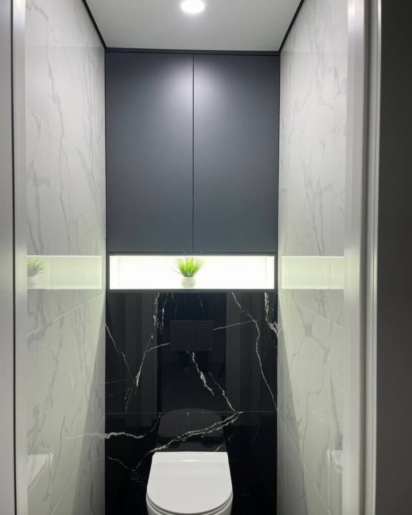 White toilet in a bathroom with white and black marble tile walls.